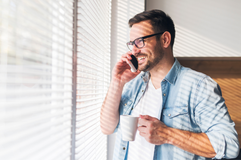 Man on the phone standing with a cup of coffee