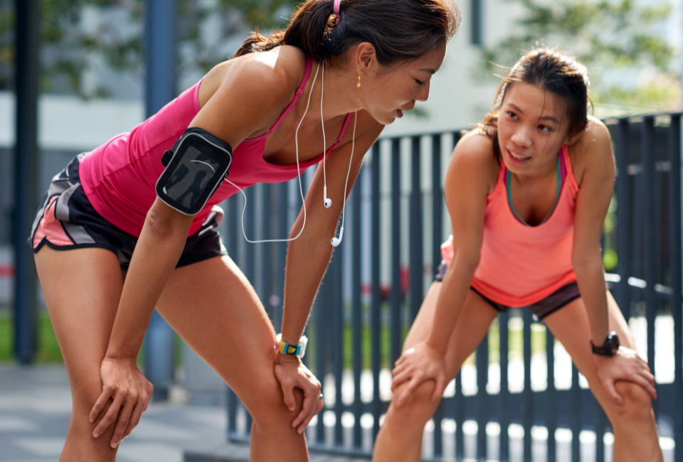 Two females runners leaning over knees tired 