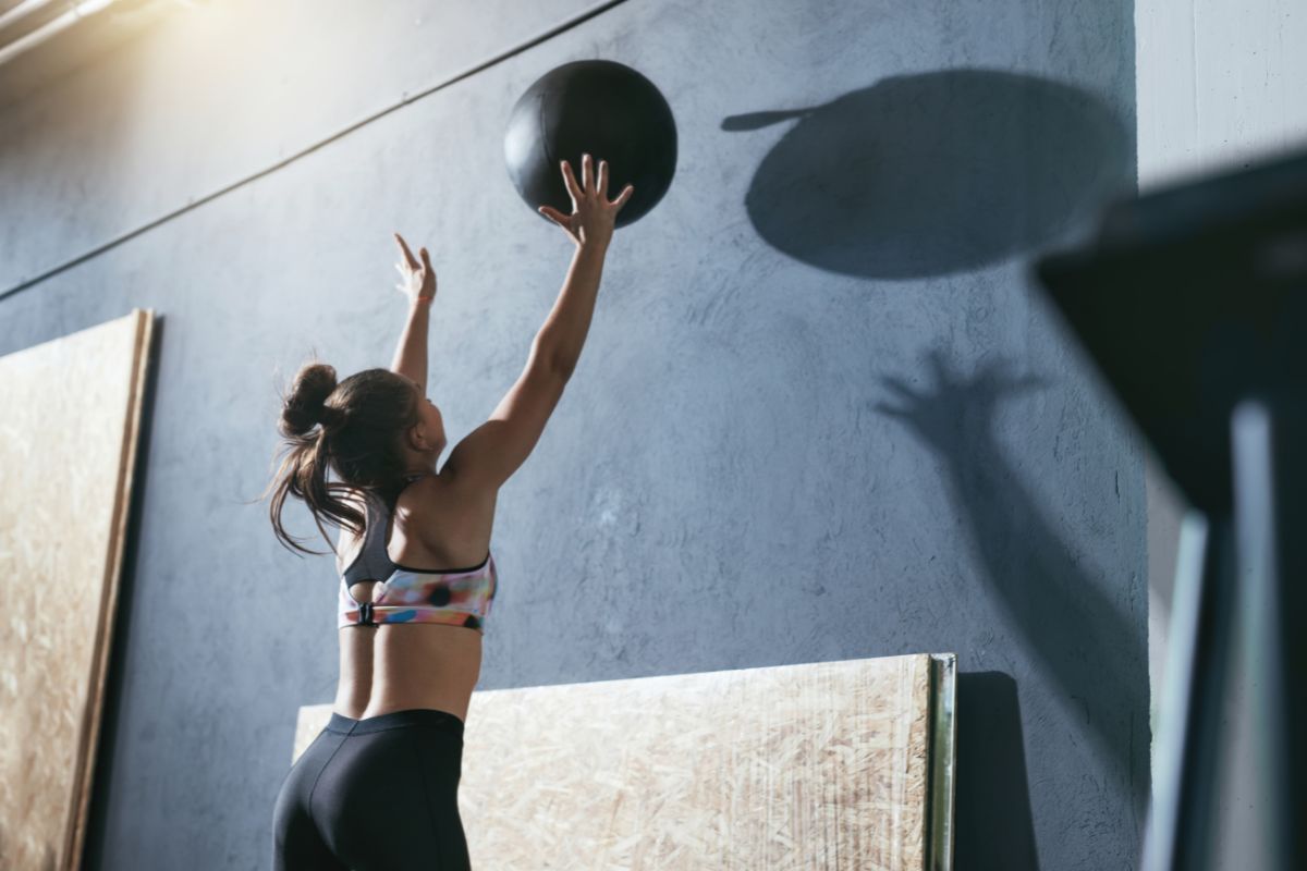 A woman throwing a wall ball up against the wall