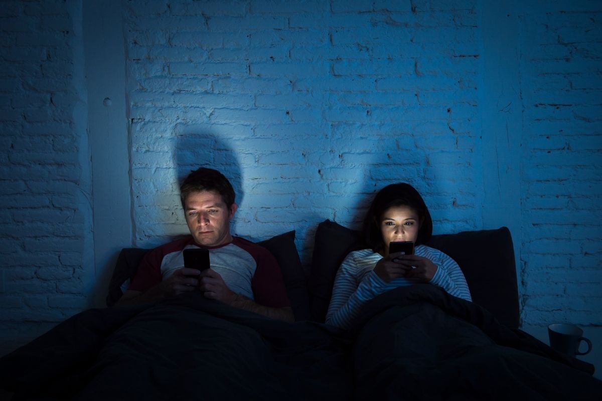 man and woman on phones in bed