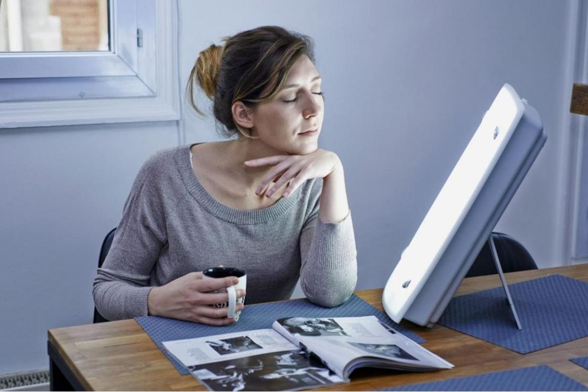 woman reading in front of light therapy lamp