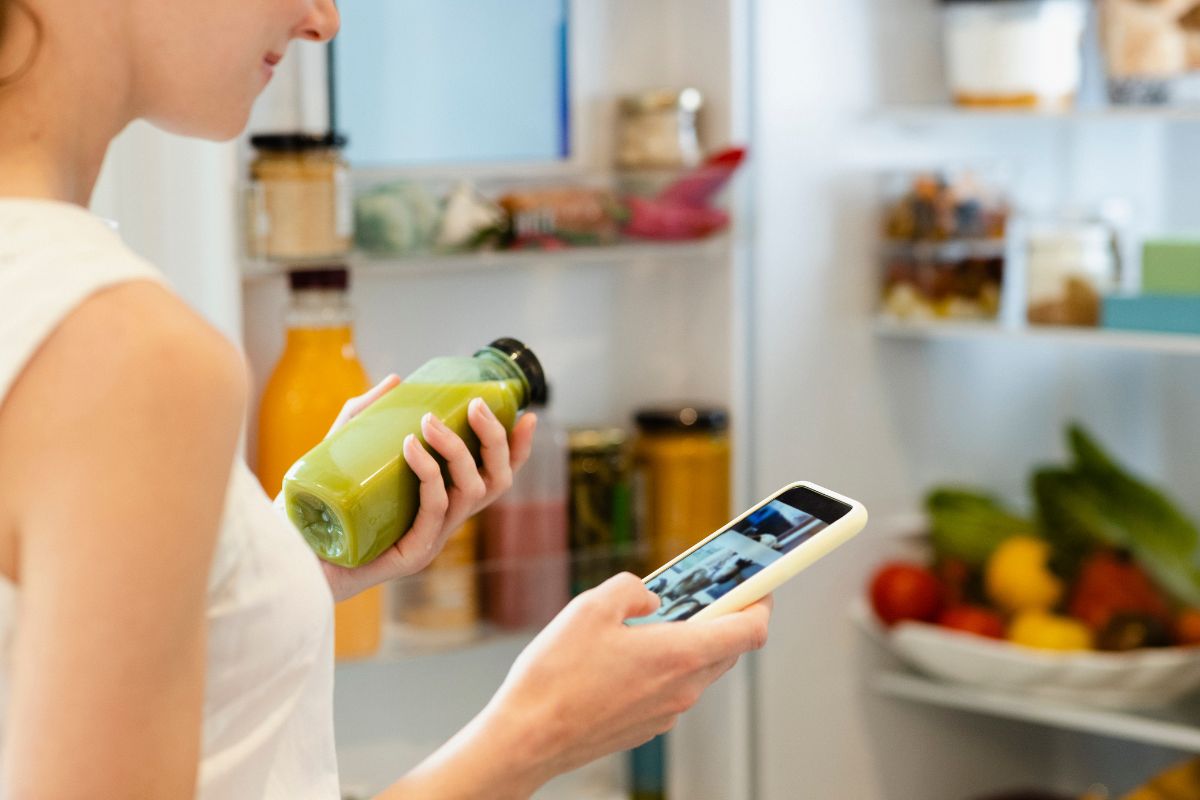 WOman checking phone for calories while getting food from cupboard
